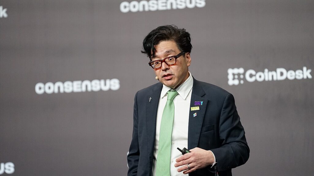 컨센서스 행사 무대에서 안경과 연두색 넥타이를 착용하고 발표하는 톰 리