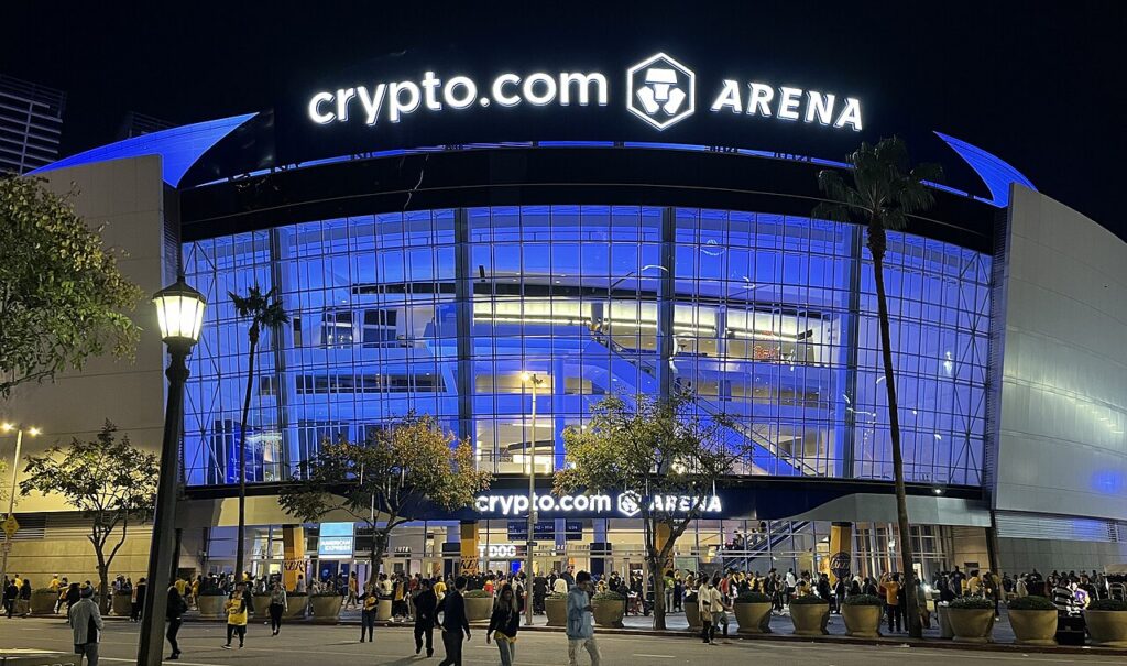 Crypto.com Arena 간판과 파란 조명의 유리 외벽, 입구 앞 사람들이 보이는 야간 외관