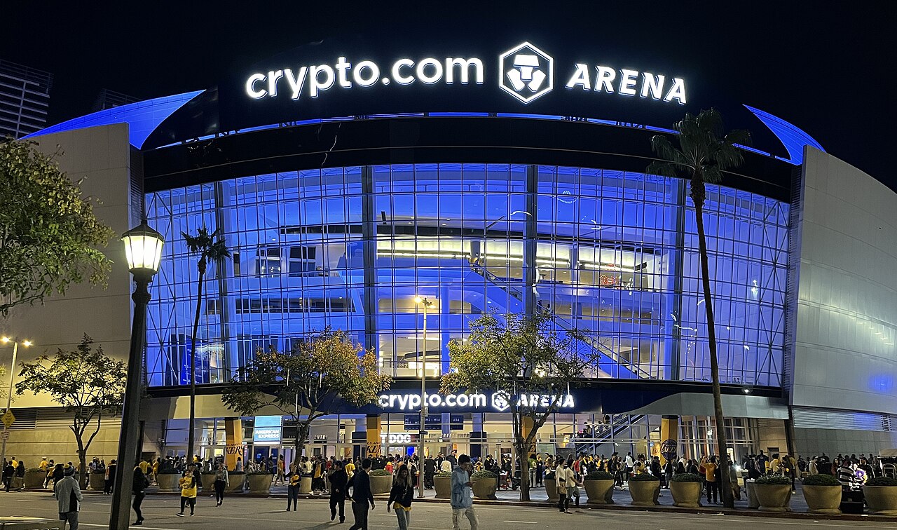 Crypto.com Arena 간판과 파란 조명이 켜진 유리 외벽, 입구 앞 사람들이 보이는 야경